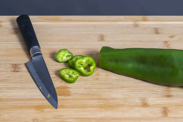 Portions of green bell pepper cut with knife on wooden kitchen board. Food preparation concept. Selective focus