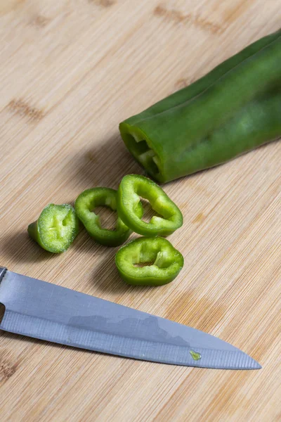 Portions of green bell pepper cut with knife on wooden kitchen board. Food preparation concept. selective focu
