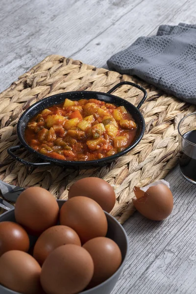 Kırmızı ve yeşil biberli, kabaklı ve soğanlı Pisto manchego (Manchego ratatouille). Yumurtalı gri kaseler. Tipik ve geleneksel İspanyol yemekleri. Yatay fotoğraf ve seçici odak