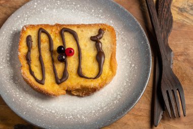 (Torrijas) Fried bread soaked in milk flavored with vanilla, cinnamon, lemon and egg with chocolate on a wooden background.Typical Easter sweet. Concept of traditional festive cuisine.Selective focus.