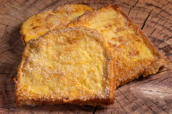 (Torrijas) Fried bread soaked in milk flavored with vanilla, cinnamon, lemon and egg on a wooden background.Typical Easter sweet. Concept of traditiona festive cuisine.Selective focus.