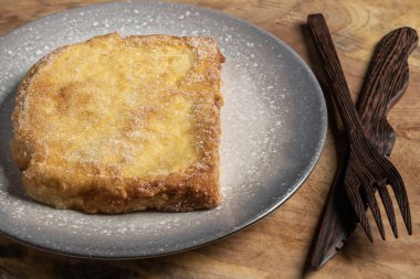 (Torrijas) Fried bread soaked in milk flavored with vanilla, cinnamon, lemon and egg on a wooden background.Typical Easter sweet. Concept of traditional festive cuisine.Selective focus.