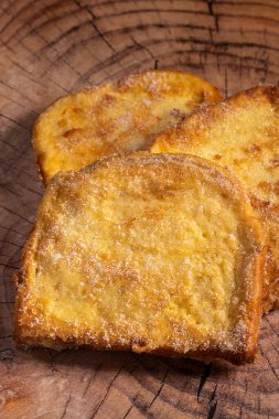 (Torrijas) Fried bread soaked in milk flavored with vanilla, cinnamon, lemon and egg on a wooden background.Typical Easter sweet. Concept of traditional festive cuisine.Selective focus.