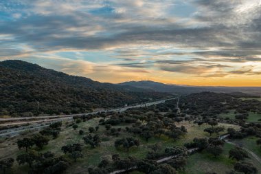 Aerial drone view of autumn landscape at sunset in northern Extremadura, Spain, with road, trees, plants and rocks. Concept of rural, healthy life, travel, transport, sport and adventure.