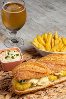 Tipik İspanyol kalamar sandviçi. Mayonez, sarımsak ve maydanozlu. Biraz kızarmış patates ve bir bardak soğuk bira. Tapas kavramı, eğlence ve gastronomi. Dikey fotoğraf ve seçici odak.