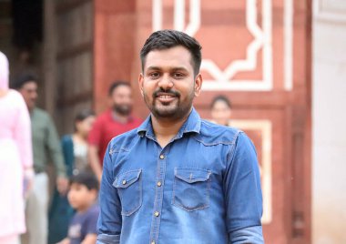 Caddenin arka planında ve bulutlu bir şehirde yaşayan yakışıklı bir Hintli adamın portresi.