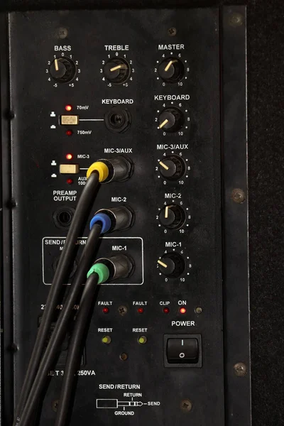 Close-up of audio mixer panel with cables in a recording studio