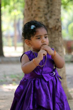 Mor bir elbise giyen ve elinde yiyecek olan küçük bir kız..