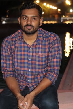 Geceleri şehirde gülümseyen genç bir adamın portresi.