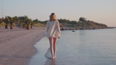 Havlu taşıyan kız sahilde yürüyor.