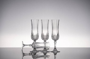 Cam kristal kadehleri kes şampanya flütü, gri arka planlı, parlak gri yüzeyde izole edilmiş..