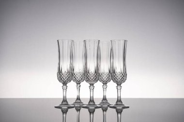 Cam kristal kadehleri kes şampanya flütü, gri arka planlı, parlak gri yüzeyde izole edilmiş..