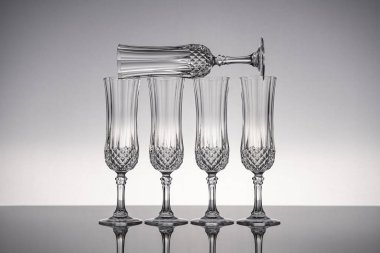 Cam kristal kadehleri kes şampanya flütü, gri arka planlı, parlak gri yüzeyde izole edilmiş..