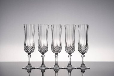 Cam kristal kadehleri kes şampanya flütü, gri arka planlı, parlak gri yüzeyde izole edilmiş..