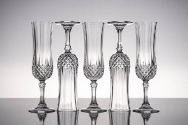 Cam kristal kadehleri kes şampanya flütü, gri arka planlı, parlak gri yüzeyde izole edilmiş..