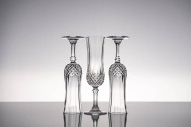 Cam kristal kadehleri kes şampanya flütü, gri arka planlı, parlak gri yüzeyde izole edilmiş..