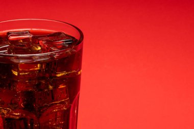 Buzlarla dolu bir bardak ve kırmızı zemin üzerinde fotokopi alanı olan taze soğuk bir kola.