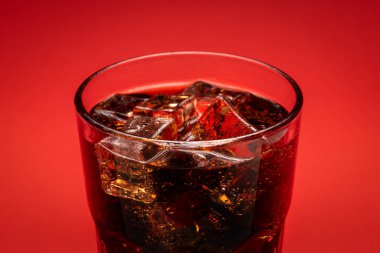 Buzla dolu bir bardak ve kırmızı zemin üzerinde taze soğuk bir kola.