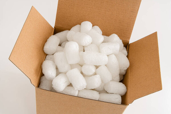 Cardboard box isolated on the white background filled with packing peanuts