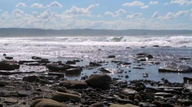 Büyük okyanus dalgaları güneşli bir günde kayalık kıyılara çarpıyor.