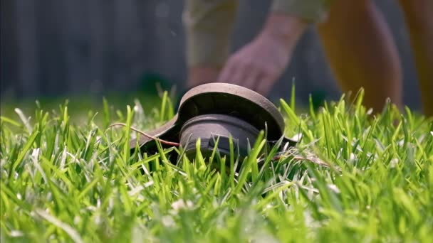 ワイパースニペットで緑の草を切る 手は芝刈り芝刈り芝生を開催しました 草の殻が飛び回り ゆっくりとガーデニングツール — ストック動画