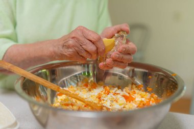 Yaşlı kadın metal kasede sebze yemeği yapıyor. Sağlıklı salata için sebze doğruyorum..