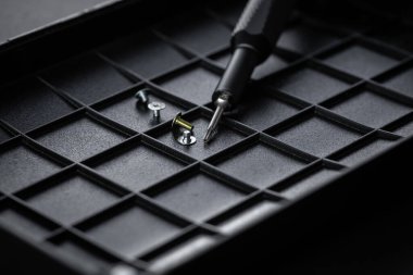 Torx sürücü biti ve alüminyum biti sürücüsü siyah sıralama tepsisinde. Vidalar ve sürücüler etrafa saçılmış. Manyetik prizli tornavida sapı ve kavrulmuş tutuşu.