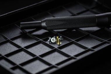 Torx sürücü biti ve alüminyum biti sürücüsü siyah sıralama tepsisinde. Vidalar ve sürücüler etrafa saçılmış. Manyetik prizli tornavida sapı ve kavrulmuş tutuşu.