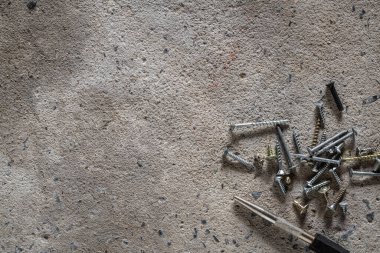 Beton kaplama arka planda vida, tırnak. Kopya alanı olan çimento zemindeki vida ve çivilerin kapatılması.