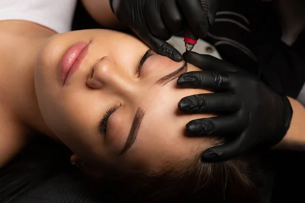 Process of creating permanent brow makeup with a machine at beauty salon. Top view