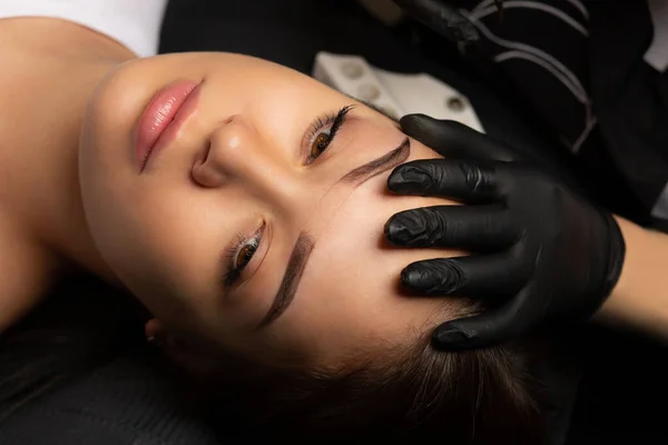 Process of creating permanent brow makeup with a machine at beauty salon. Closeup shot