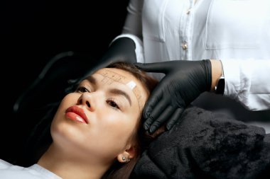 Measuring the angle and forming the shape of the eyebrows during the microblading procedure