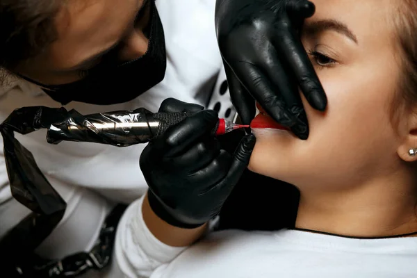 Beauty specialist applying permanent ink to the woman\'s lips at beauty salon. Closeup shot