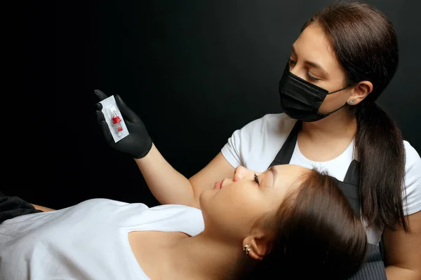 Permanent makeup master shows sterile needle to a client. Preparation to the beauty procedure