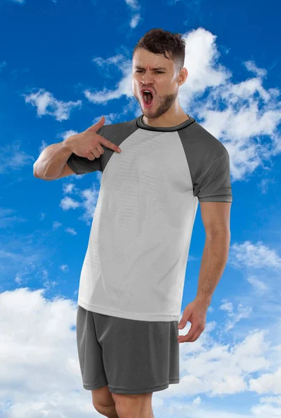 ポーランド代表チームの白とグレーのTシャツを着たプロのサッカー選手は 雲の中で空を背景に反抗と幸福の表現でゴールを決めたことに興奮して叫んでいます — ストック写真