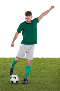 Yeşil Suudi Arabistan milli takımının formasına sahip profesyonel futbolcu beyaz arka planda meydan okuma ve karar ifadesinde bir gol atmak üzere..