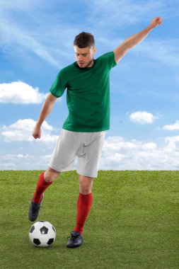 Yeşil Meksika milli takımının formasına sahip profesyonel futbolcu beyaz arka planda meydan okuma ve karar ifadesiyle gol atmak üzere..