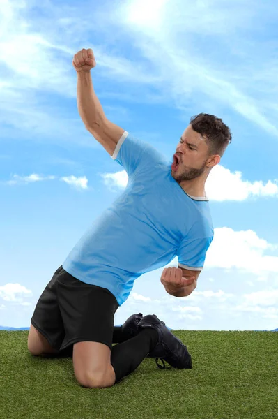职业足球运动员 略带蓝色的乌拉圭国家队球衣 为进球而激动地大喊 在球场的草场和云彩的背景下表现出挑战和快乐 — 图库照片