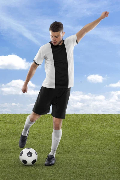 Professional soccer player with white and black Germany national team jersey about to score a goal with an expression of challenge and decision on his face on field grass and cloud background