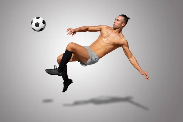Athletic man without jersey soccer player jumping about to kick the ball on gray gradient background.