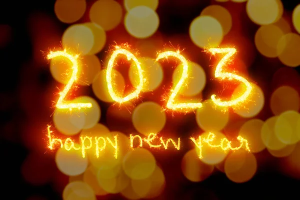 Defocused lights background with fireworks text wishing a happy new year 2023.