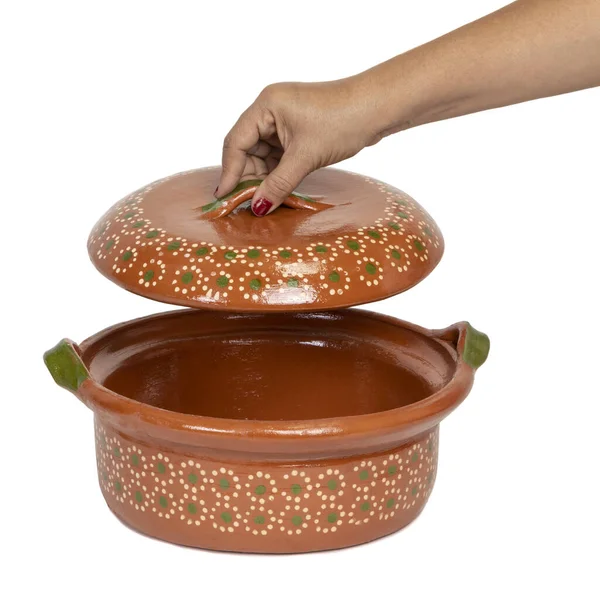 Woman\'s hand Handmade red clay pot made in Mexico. Traditional handmade Mexican clay crockery. isolated White background.