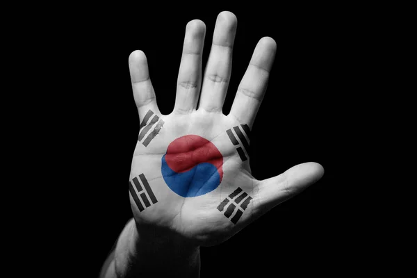 Rude man hand with flag of Korea Republic in stop sign to anger, discrimination, racism, abuse on black background.