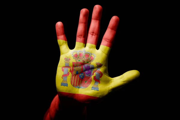 Rude man hand with flag of Spain in stop sign to anger, discrimination, racism, abuse on black background.