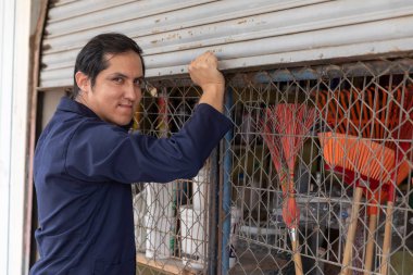 Yakışıklı bir işadamı, donanım ürünleriyle dolu işinde neşe, mutluluk ve gurur dolu bir ifadeyle işini açıyor..