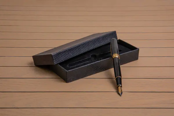 黑色优雅金属钢笔 金质细部 木制衬底为黑色天鹅绒盒 图库图片