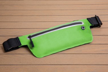 yeşil yumuşak bel çantası, ahşap arka planda bel fermuarı.