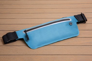 Mavi yumuşak bel çantası, ahşap arka planda bel fermuarı.