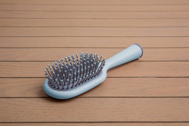 Ahşap arka planda gri detayları olan mavi plastik tarak.