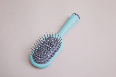 Bej arka planda gri detaylar içeren pembe plastik tarak. 